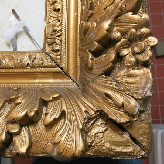 The right lower corner of the frame before restoration, showing severe losses of ornaments and previous crude repairs.