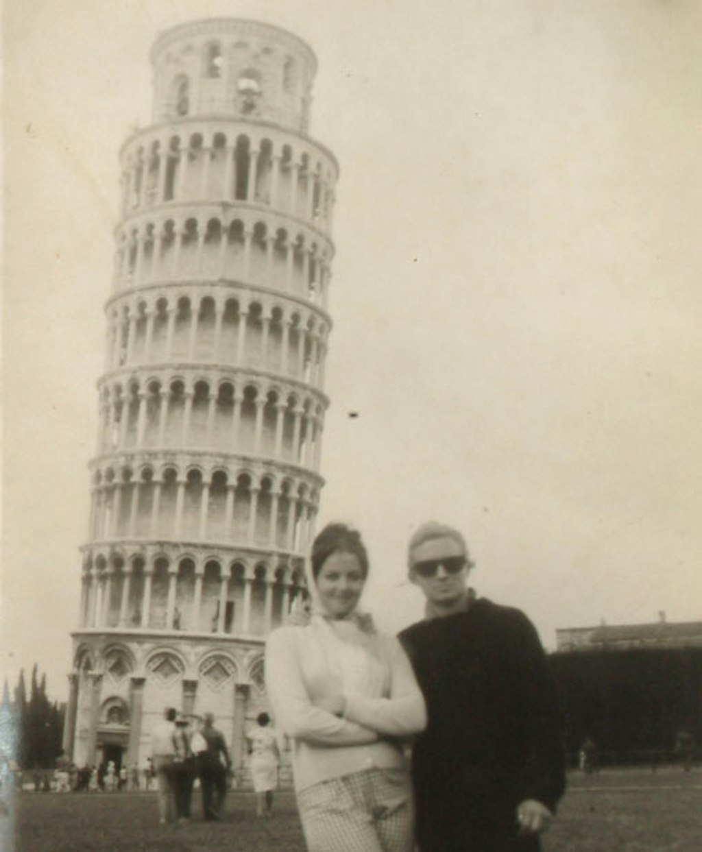Two people stand in front of the Leaning Tower of Pisa
