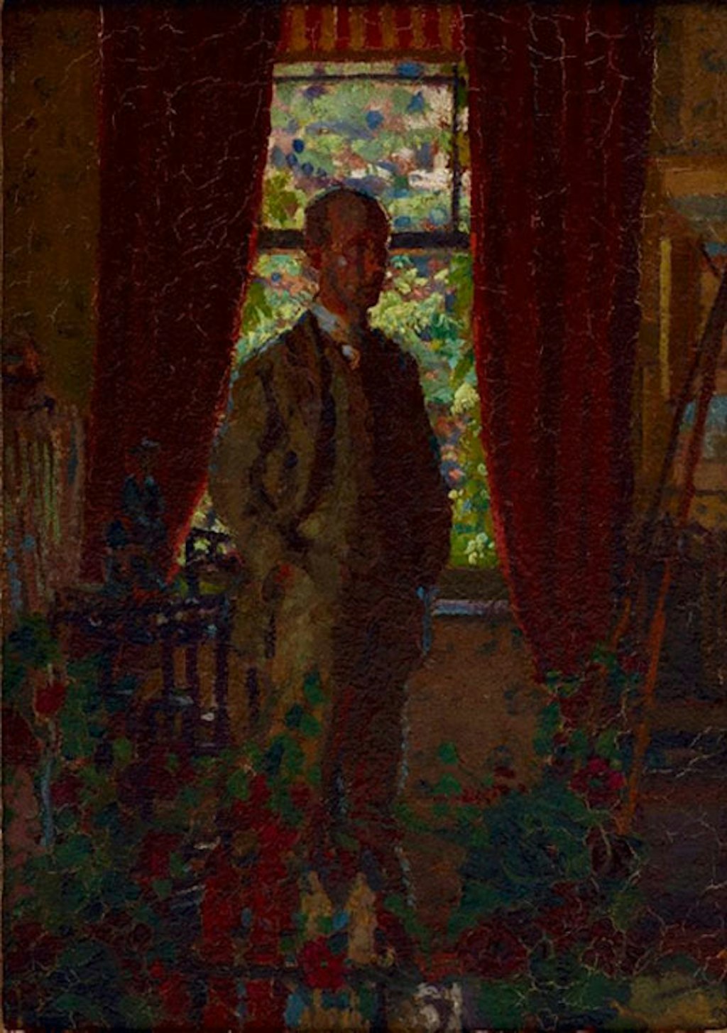 A person in a three-piece suit and tie stands in front of a window in a domestic setting. The light outside is bright and the room dark.