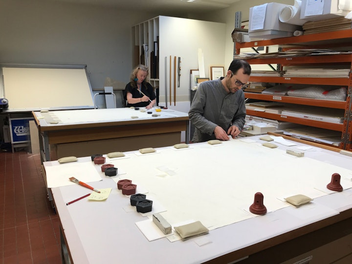 The paper hinges are applied to the drawings in the conservation lab
