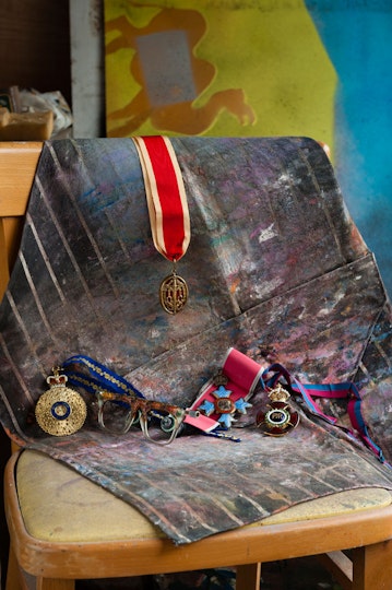 Nolan's medals, from left to right: 
                                                AC (Companion of the Order of Australia)
                                                Knighthood (Knight Bachelor) - over the back of the chair
                                                CBE (Commander of the British Empire)
                                                OM (Order of Merit)