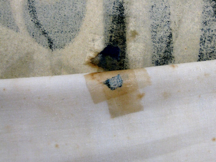 h3. Previous repairs revealed
Removing the linen also detached some previous repairs: in this case, tape along with a small part of the poster it had been securing in place, which was reattached later.