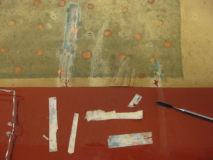 h3. Removing old repairs
Other tape repairs were removed with a scalpel or a spatula. Here, this revealed previous retouchings, which can be seen as blue staining on the back of the work.