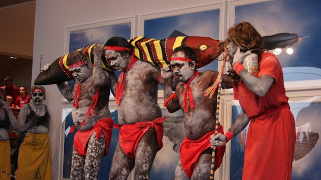 Four dancers from the remote community of Warmun (Turkey Creek)  standing on a stage.