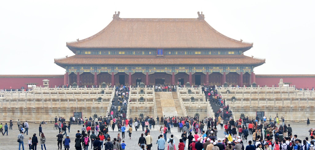 Crowds of people in front of a large Chinese palace building at the top of several sets of stairs.