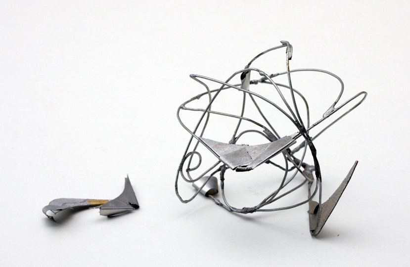 A detached piece lies beside a silver-coloured wire sculpture