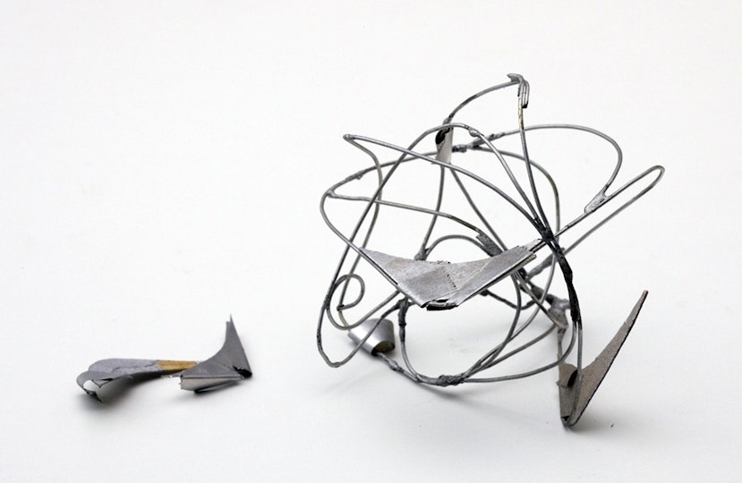 A detached piece lies beside a silver-coloured wire sculpture