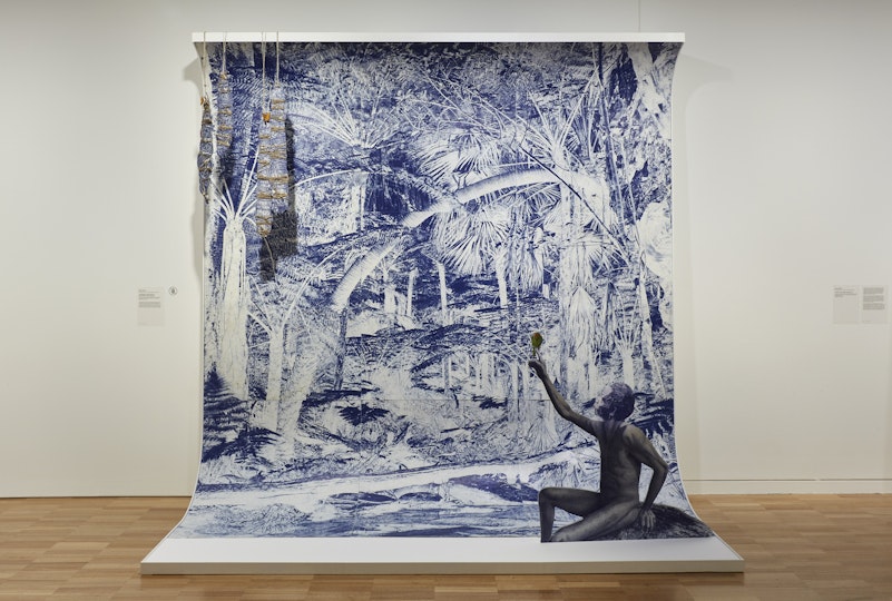 A blue-and-white drawing on a curved white support with a figure of a seated Aboriginal man in the foreground with a bird on his outstretched finger.