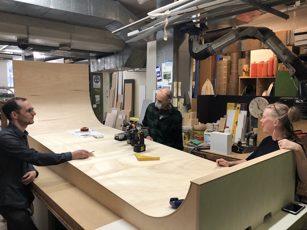 The plywood surface is added to the curved panel framework in the Gallery workshop