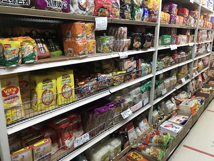 Shelves in an Asian grocery stocked with packets of dried noodles.