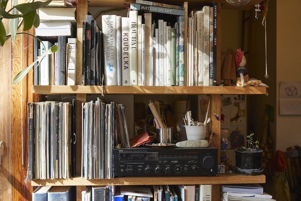 A shelf holding various items including books, magazines and a stereo.