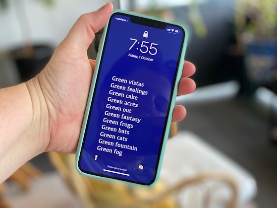 A hand holding a smartphone showing a dark blue screen with white text.