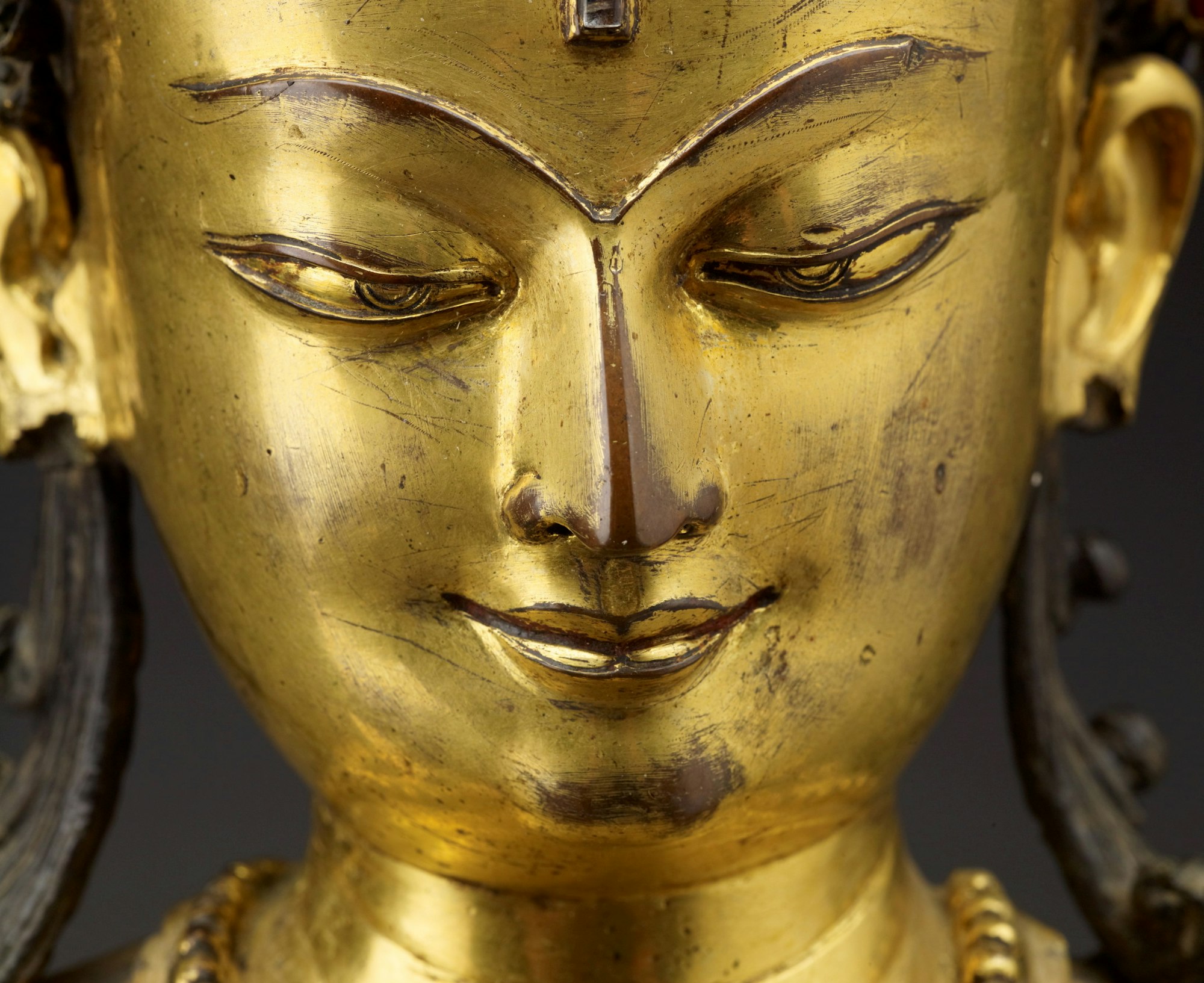 Face of a gold-coloured Bodhisattva statue.