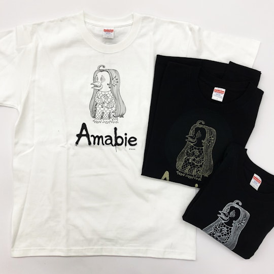 One white T-shirt and two folded black T-shirts, all featuring an illustration of an Amabie.