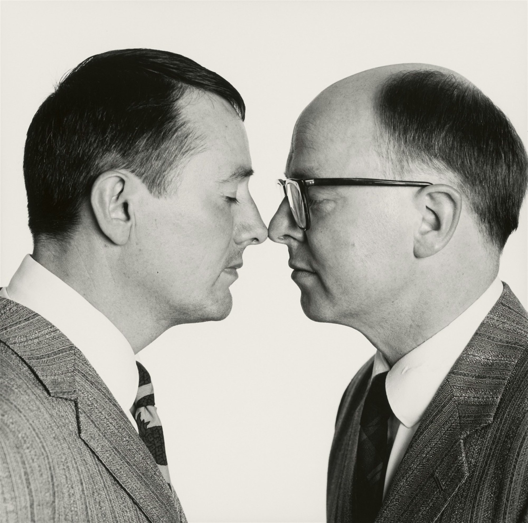 Black-and-white photo of two people facing each other, their eyes closed, the tips of their noses touching.