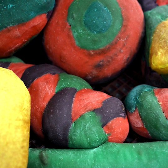 A cluster of multi-coloured dough forms. One is a sphere in concentric circles and another is a plaited length.