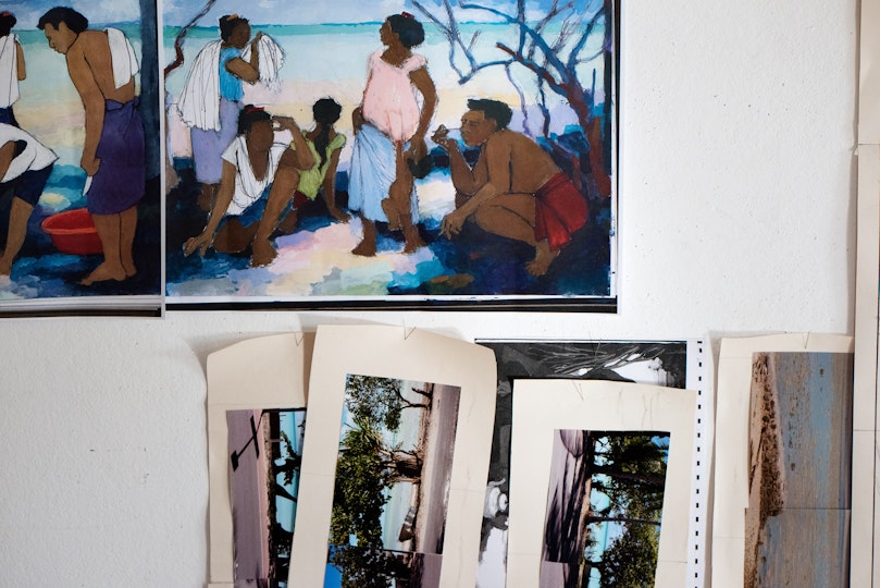 Two artwork images are fixed to a wall. Underneath several photos are pinned.
