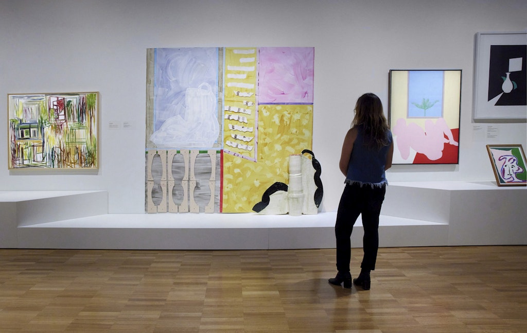 A visitor stands in front of several contemporary artworks in a gallery.