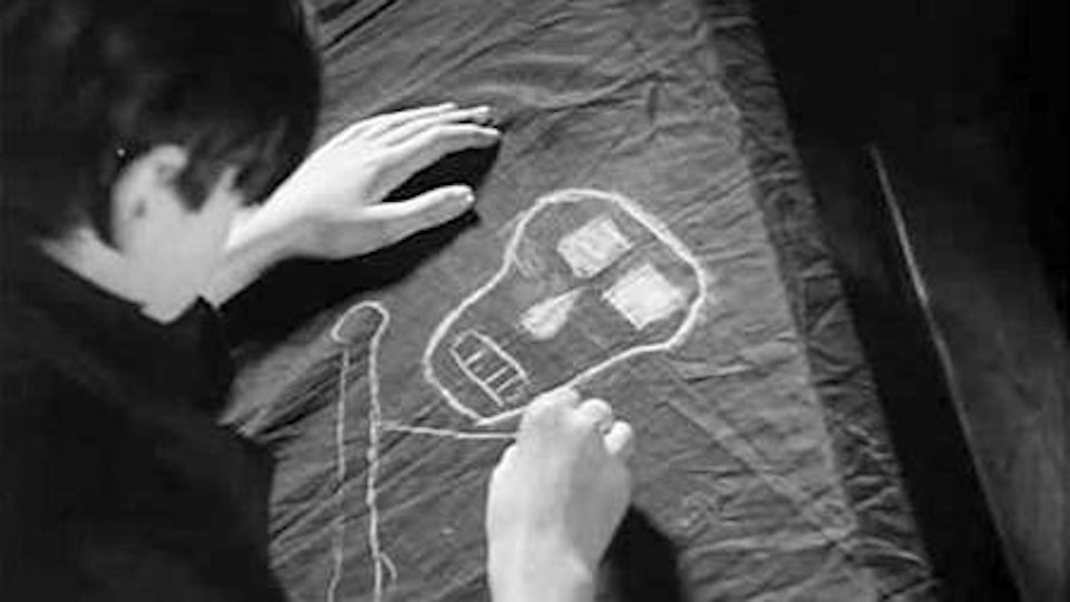 A person drawing a skull and crossbones on a piece of fabric.
