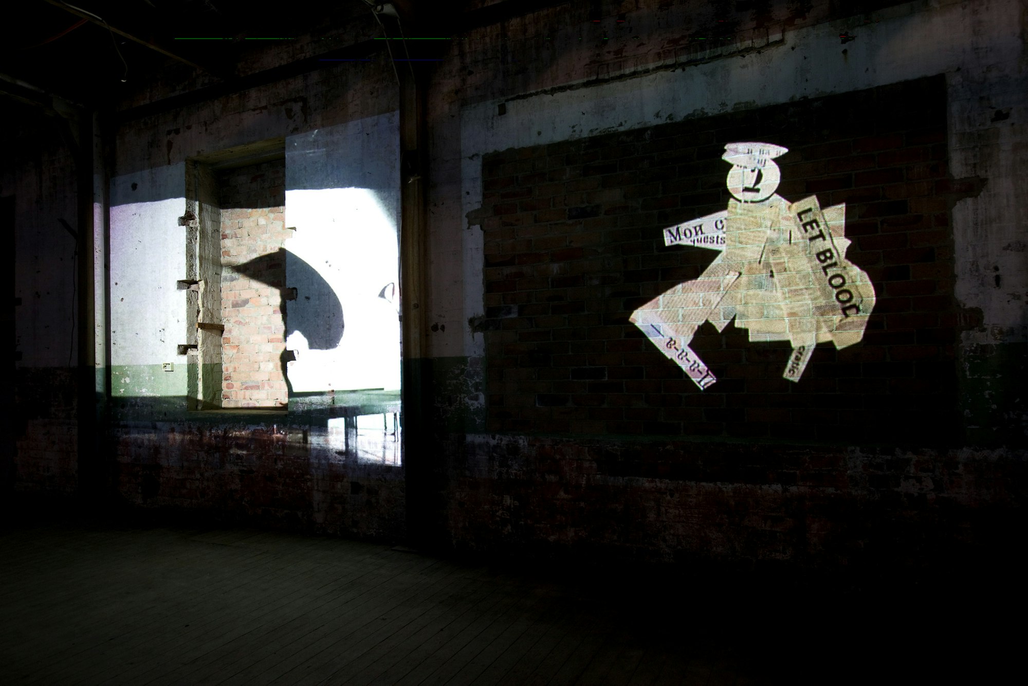 A projection on a wall showing a figure made out of newspaper cuttings.
