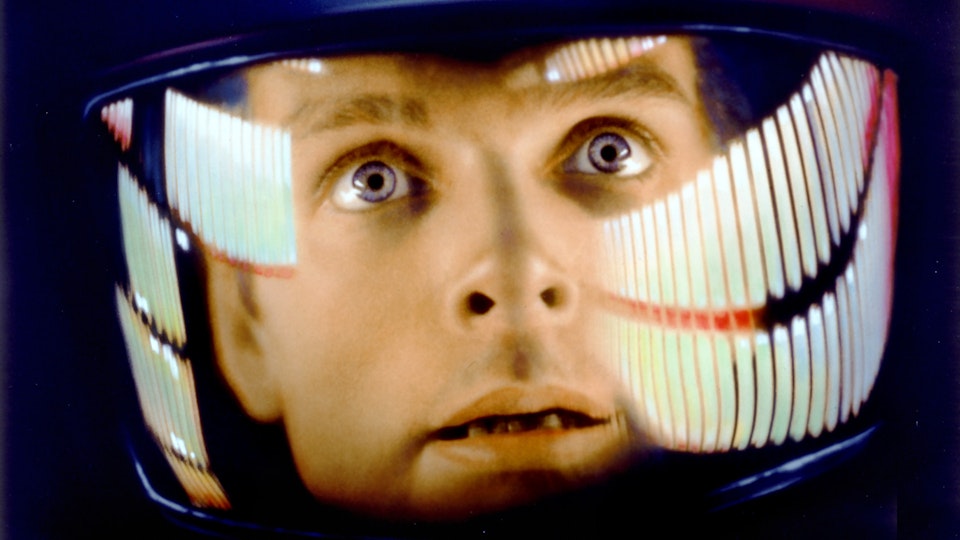 A close-up of a person's face with light skin who is wearing an astronaut helmet.
