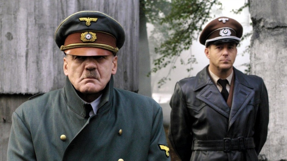 Adolf Hitler and a Nazi officer stand outside.