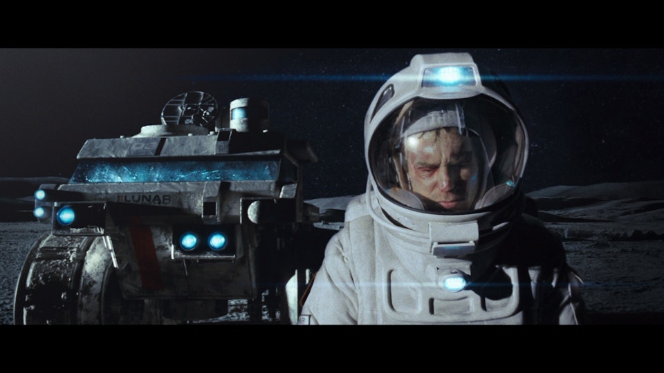 An astronaut walks ahead of a space rover.