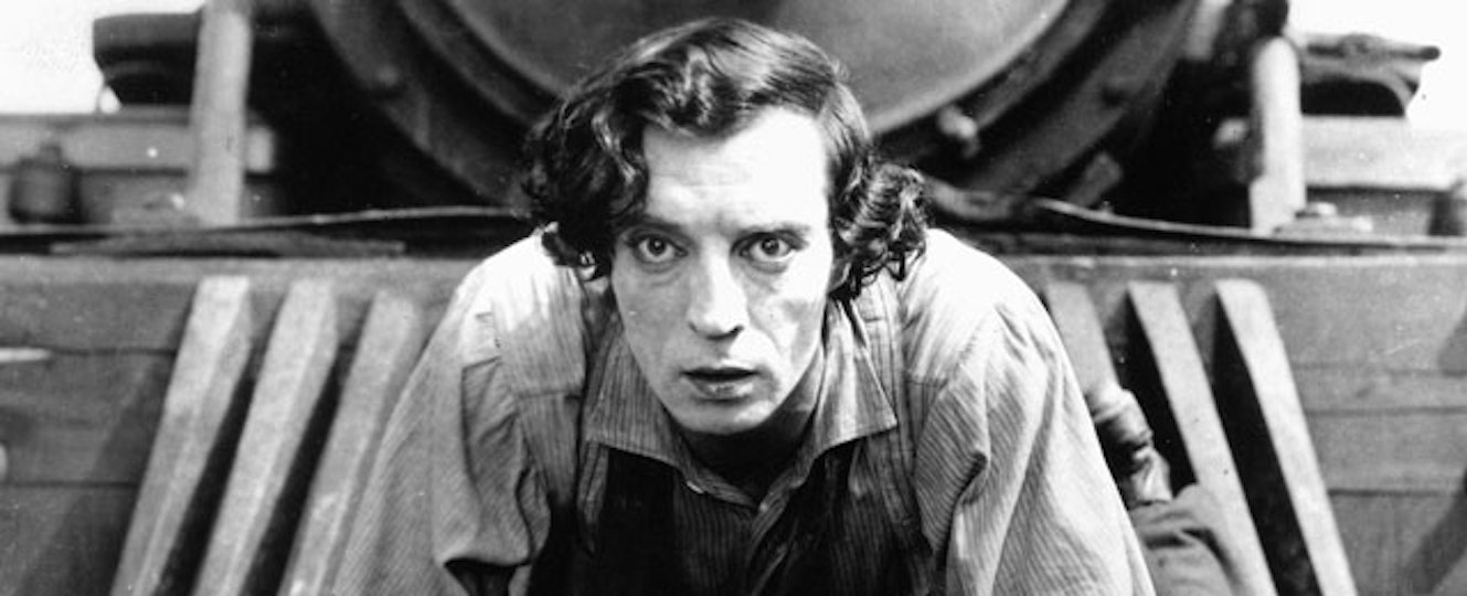 A person with light skin is bent down. Close behind them is a train.