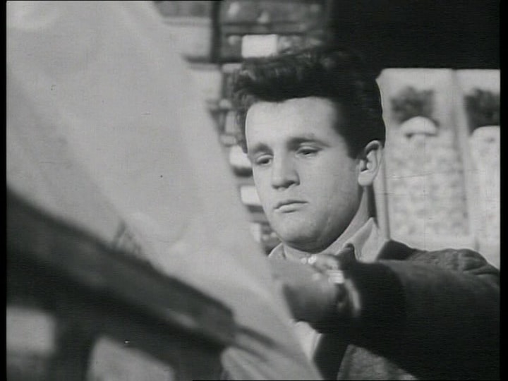 a person with short dark hair reaches their left arm out to a large surface in front of them.