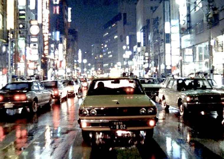 A busy city road at night on which cars are bumper-to-bumper.