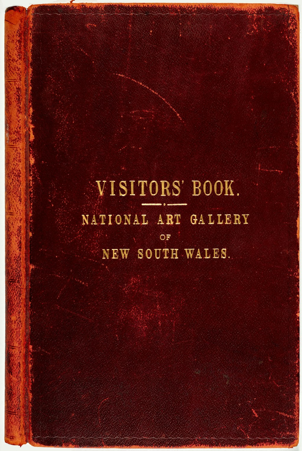 A closed book with a worn red cloth cover, inscribed on the front in gold lettering 'Visitors' Book. National Art Gallery of New South Wales'