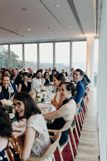 Dozens of smiling and laughing people sit at tables in a restaurant.