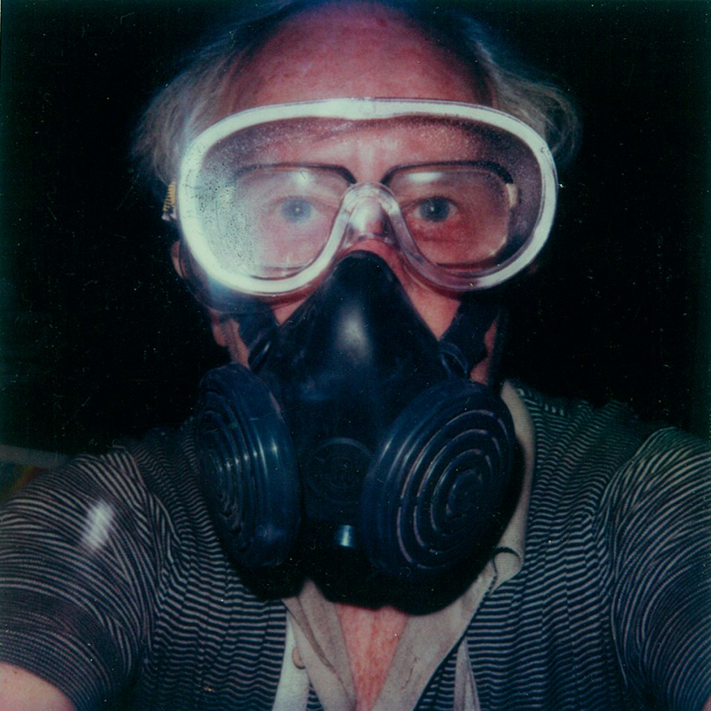 A head and shoulder photograph of a person wearing goggles and a respirator mask.