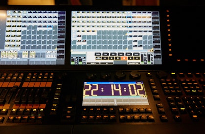 A control desk with multiple screens, buttons and switches.