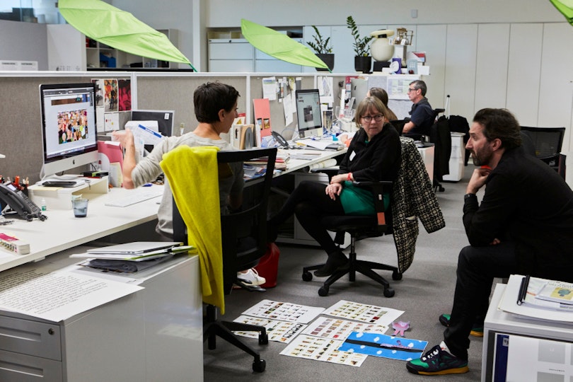 Three people sit in discussion in an office.