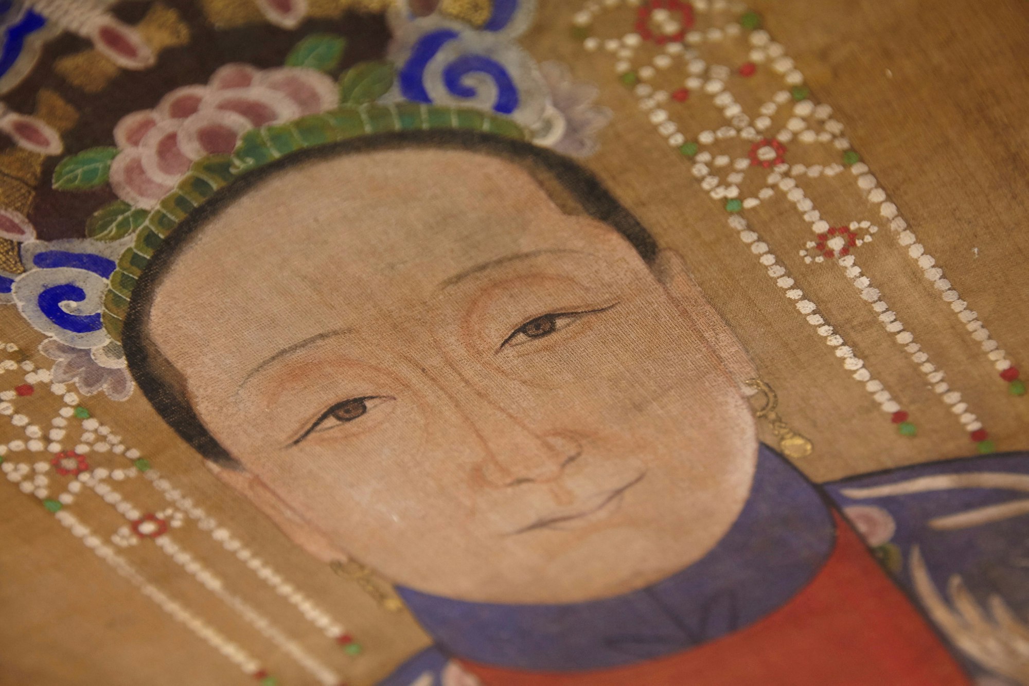 The head and neck of a person wearing dangling earrings and an ornate headdress.