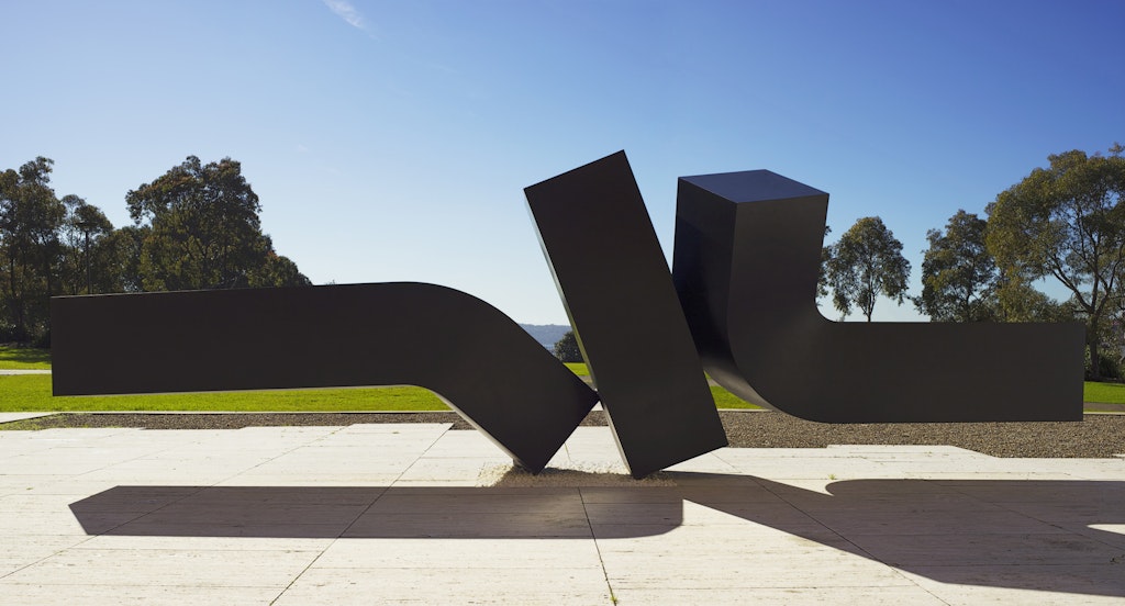 A massive sculpture of three black rectangular shapes, each one touching another at a point