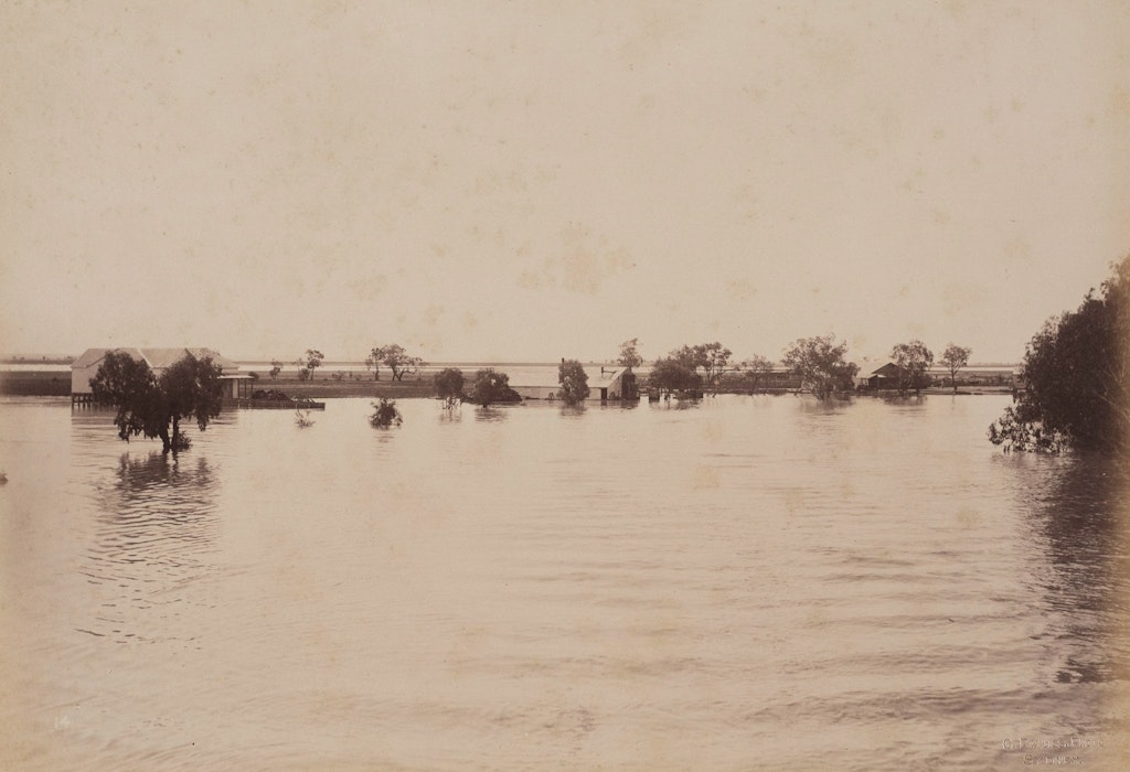 [w:74.1984.14[Woolsheds Dunlop Station, Darling River (first view)]] 1886. One of a series of photographs in the Gallery’s collection taken by Charles Bayliss of the Darling River in flood, four years before the flood Piguenit painted. 