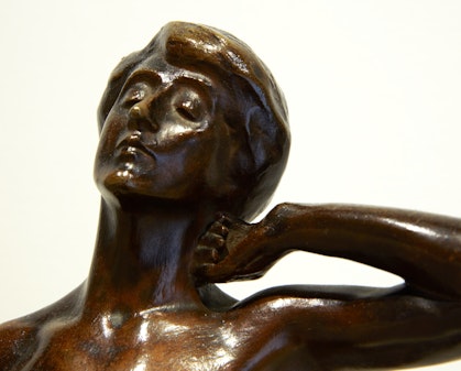 The head and shoulders of a bronze figure. Their eyes are closed, their head leans back and their left hand rests on the side of their neck.