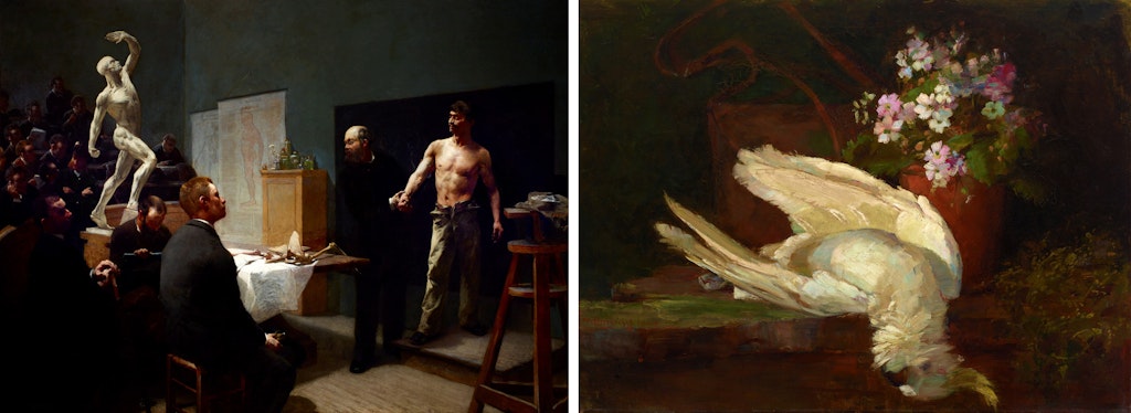 People seated in a room look at a person in a suit holding the arm of a shirtless person. A dead bird lies on a table next to a pot of flowers.