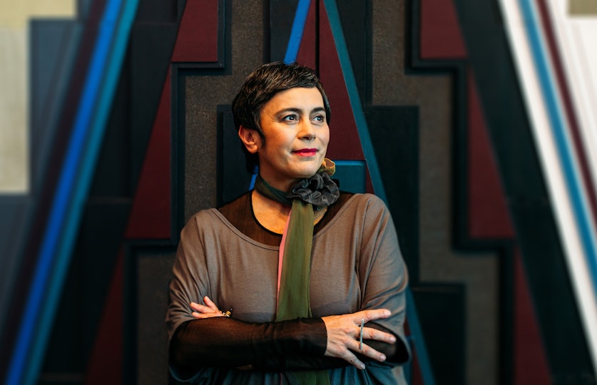A person with short hair wearing a scarf around their neck.
