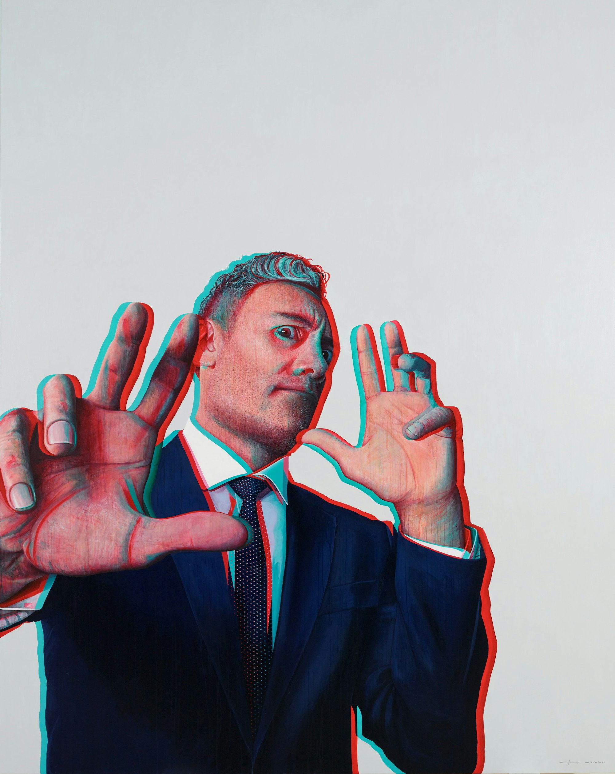 A person with short hair, dressed in a white shirt and dark jacket and tie, holds their hands up in front of their face while leaning back.