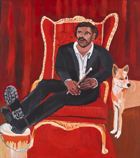 A person sits on a throne holding a paintbrush with their feet resting on a paint can. A dingo stands beside them.