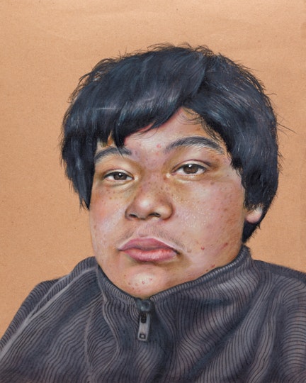The head and shoulders of a short-haired person wearing a zipped-up, high-necked top