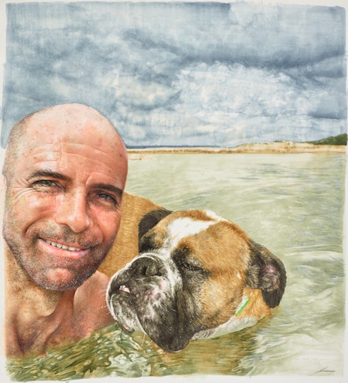 A bald bearded person in the sea with a dog