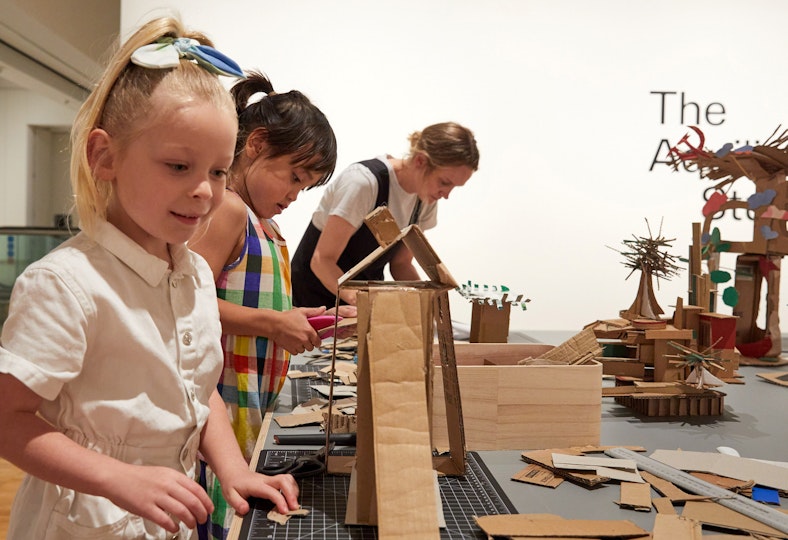 Two children and an adult at a worktable making cardboard constructions