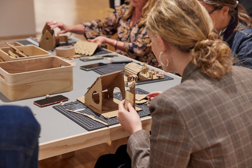 People sit at a table making structures out of cardboard