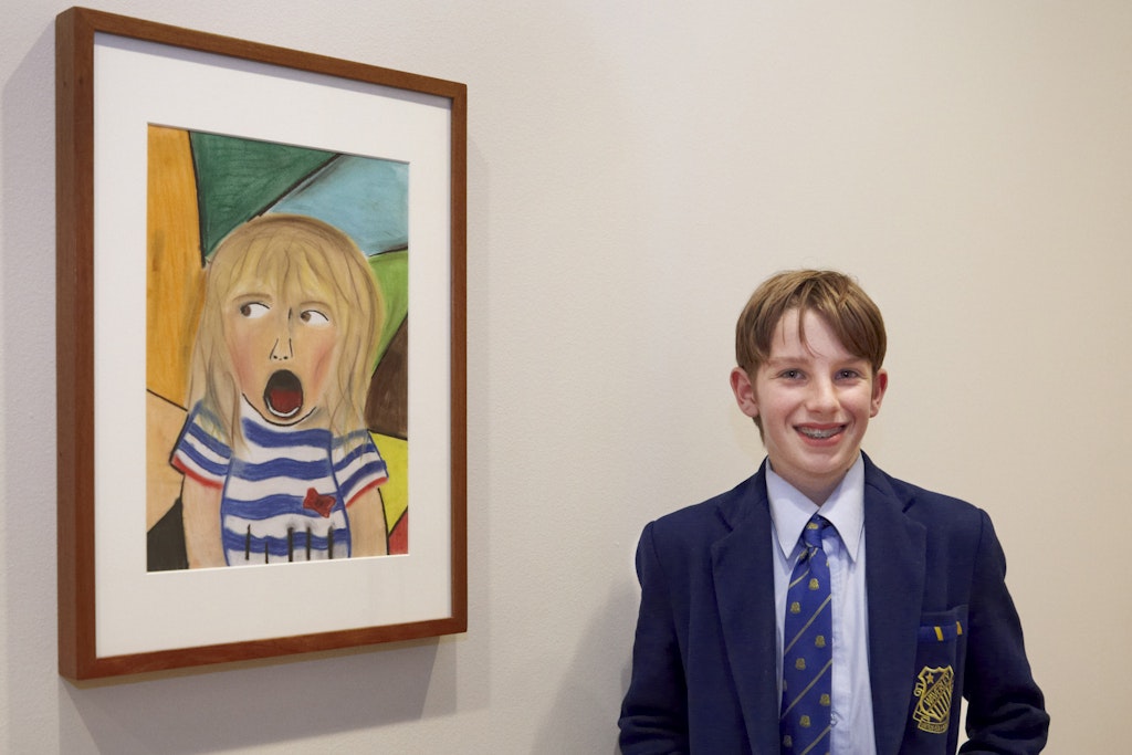 A young person in a school blazer, tie and shirt stands next to a portrait of an open-mouthed person in a striped t-shirt