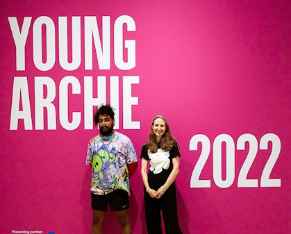Two people stand in front of a wall on which is written Young Archie 2022, presenting partner ANZ