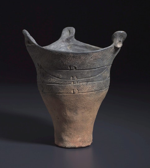 An earthware three-pointed vessel with a simple pattern and lines on the upper half